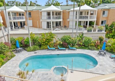 Pool area with pool, spa, loungers, table seating, umbrellas, and surrounding property at Serenity Apartments Noosa accommodation